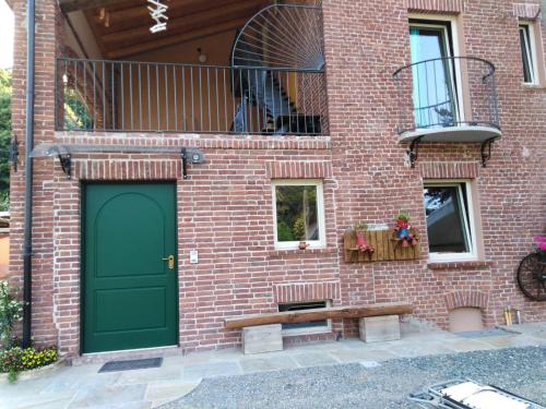 um edifício de tijolos com uma porta verde e um banco em LA LEGIUN STRANIERA em Boves
