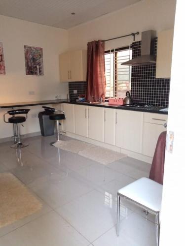 a kitchen with white cabinets and tables and chairs at Portersville Private Lodge in Freetown