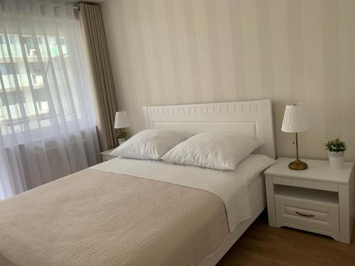 - une chambre blanche avec un lit blanc et une fenêtre dans l'établissement Apartament Bliżej Morza, à Kołobrzeg
