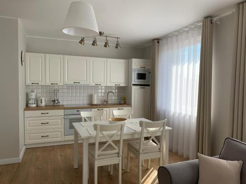 - une cuisine avec une table et des chaises blanches dans la chambre dans l'établissement Apartament Bliżej Morza, à Kołobrzeg
