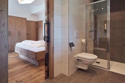 a bathroom with a shower and a toilet and a bed at Hotel Gasthof Schützenhof in Grossarl