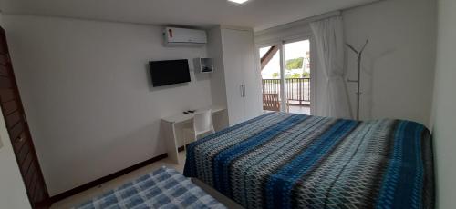 Schlafzimmer mit einem Bett, einem TV und einem Fenster in der Unterkunft Flat Praia dos Carneiros in Tamandaré