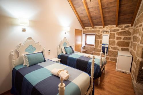 two beds in a room with a stone wall at Casa do Morgado in Mondim de Basto