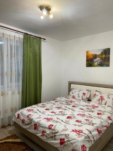 a bedroom with a bed with red flowers on it at 5 Residence Apartment in Cavnic