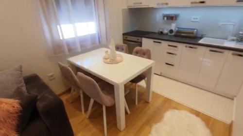 Il comprend une petite cuisine avec une table et des chaises blanches. dans l'établissement Apartman Jovana, à Zlatibor