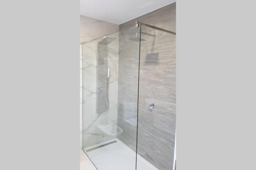 a bathroom with a shower with a glass door at Pé n'Areia Guesthouse in Vila do Conde
