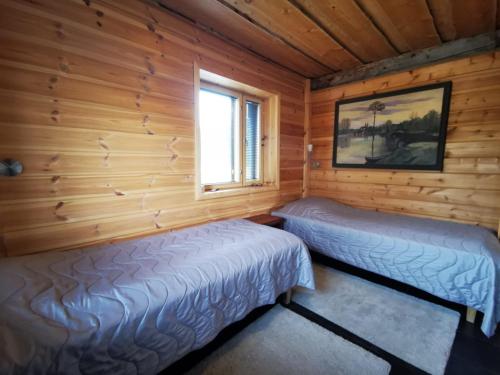 Nuorgam的住宿－Tenon Temppeli - Tilava huvila Lapissa，小木屋内的两张床,设有窗户