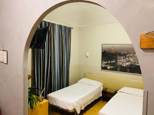 a room with two beds and an arched doorway at Hotel Ferrucci in Turin