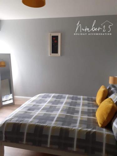 a bedroom with a bed with yellow pillows on it at Number 25 Self Catering Apartments Ederney in Ardess