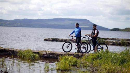 two men standing with their bikes on a pier by the water at Number 25 Self Catering Apartments Ederney in Ardess