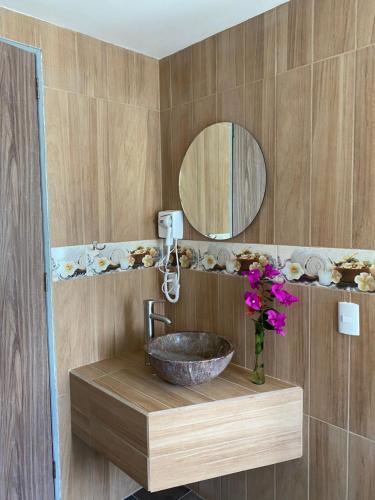 a bathroom with a sink and a mirror and flowers at Hotel & Suites Cerro Roj0 in Tlatlauquitepec
