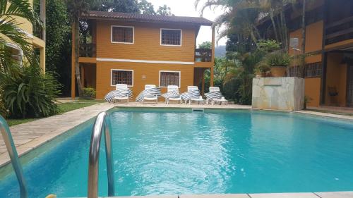 a swimming pool with chairs and a house at Vila da Praia in Boicucanga