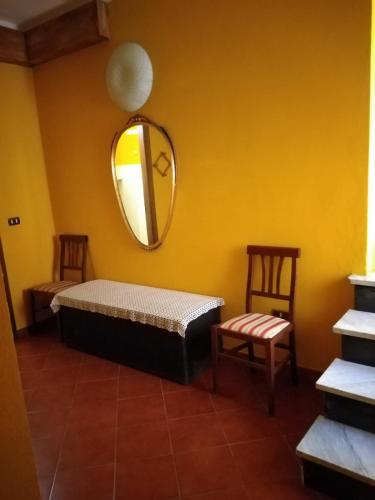 a room with a bed and a mirror and two chairs at Appartamento Oleandro in Montale