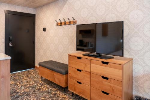 a bedroom with a dresser with a tv on top of it at The Dorothy Motel in Banff