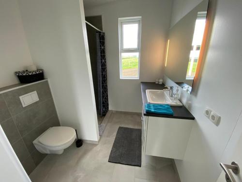 a white bathroom with a toilet and a sink at Skeiðvellir Panorama house in Hella