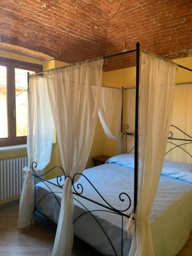 een slaapkamer met een hemelbed en witte gordijnen bij Alloggio Berenice in Villafranca Piemonte