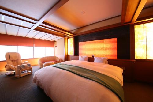 a bedroom with a large bed and a chair at Hotel Tamanoyu in Matsumoto