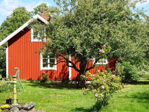 una casa roja con un árbol delante en 6 person holiday home in INGATORP, en Ingatorp