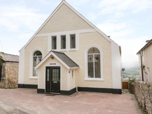 a white church with a black door on a street at Saron Chapel in Llandudno