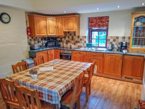a kitchen with a table and wooden cabinets at Tailor's Cottage in Abbey-Cwmhir