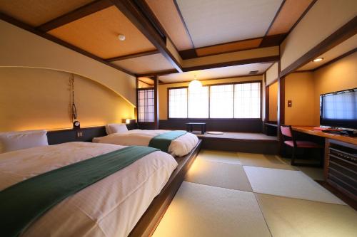 a hotel room with two beds and a television at Hotel Tamanoyu in Matsumoto