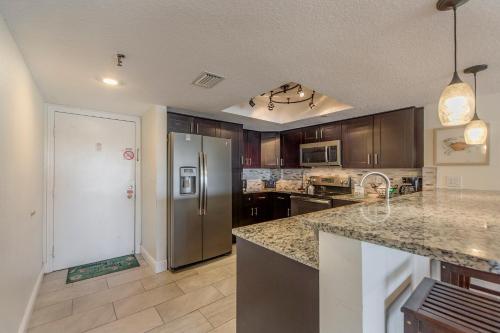 a kitchen with a stainless steel refrigerator and wooden cabinets at 102 Beach Place Condos in St. Pete Beach