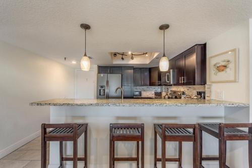a kitchen with a counter with three bar stools at 102 Beach Place Condos in St. Pete Beach