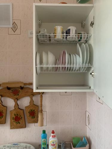 un armario de cocina con platos y tazas. en Ореховая горка Апартаменты с балконом и лифтом, en Narva