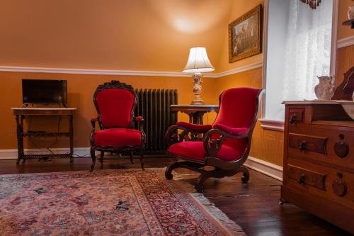 米堤亞的住宿－Gifford-Risley House Bed and Breakfast，客厅配有2把红色椅子和电视