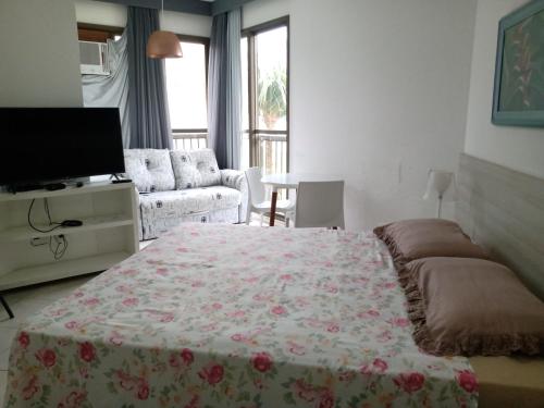 um quarto com uma cama, uma televisão e um sofá em Condado Aldeia dos Reis SAHY em Mangaratiba