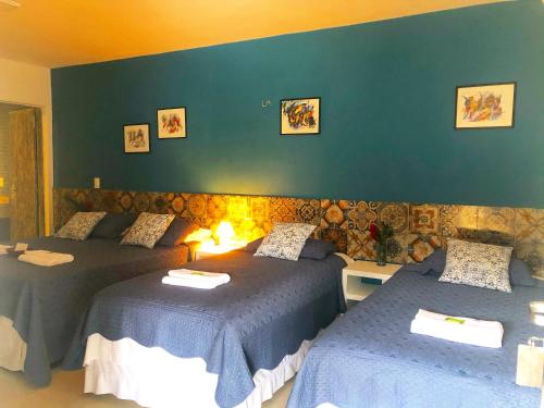 a bedroom with two beds and a green wall at Pousada Manjericão in Guaramiranga