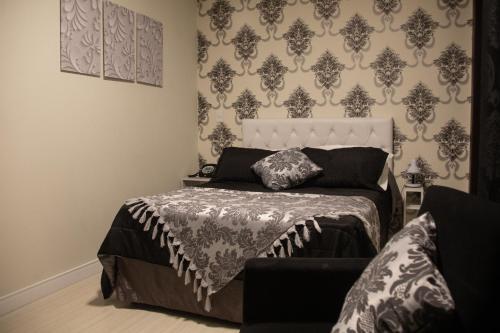 a bedroom with a bed and a wall with wallpaper at Hotel Brasilia Curitiba in Curitiba