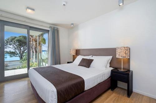 1 dormitorio con cama grande y ventana grande en 216 Serenity at Sea Spray - Paihia Apartment, en Paihia