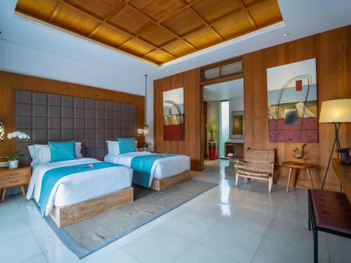 a bedroom with two beds and a desk at Villa Cendrawasih in Seminyak