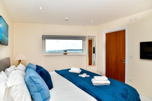 a bedroom with a blue bed with towels on it at Just Stay Wales - Meridian Quay Penthouses in Swansea