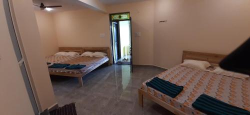 a room with two beds and a mirror at Godwill Kimo Guest house Seraulim in Madgaon