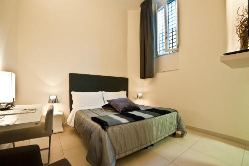 a bedroom with a bed and a desk and a window at Town House Cavour in Reggio Calabria