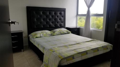 1 dormitorio con 1 cama con cabecero negro y ventana en Apartamento Armenia, como en casa!, en Armenia
