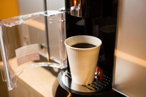 uma chávena de café sentada em cima de uma máquina de café em Tosei Hotel Cocone Ueno Okachimachi em Tóquio