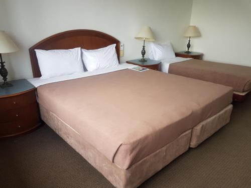 two beds in a hotel room with two lamps at Great Southern Hotel Brisbane in Brisbane