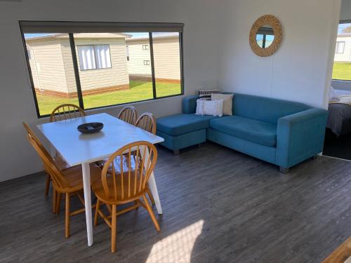 a living room with a couch and a table and chairs at Swansea Holiday Park Tasmania in Swansea