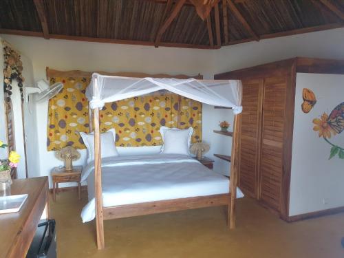 1 dormitorio con 1 cama con dosel en villa nosy détente, en Nosy Be