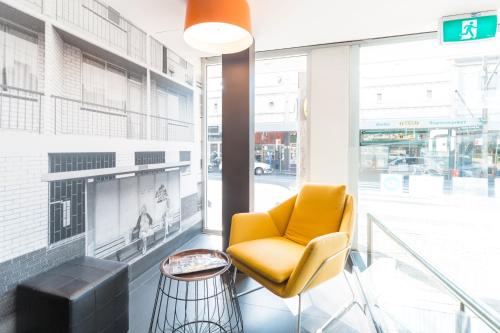 a lobby with a yellow chair and a television at Haven Glebe in Sydney