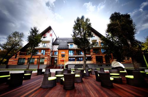 a group of chairs sitting on a deck in front of a building at Hotel Piwniczna SPA&Conference in Piwniczna