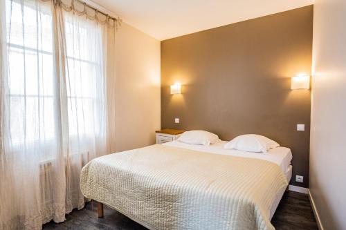 sypialnia z łóżkiem i dużym oknem w obiekcie Appart'Hotel Saint-Michel w mieście Chartres