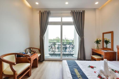 a bedroom with a bed and a desk and a window at Paradise Cu Chi Hotel in Củ Chi