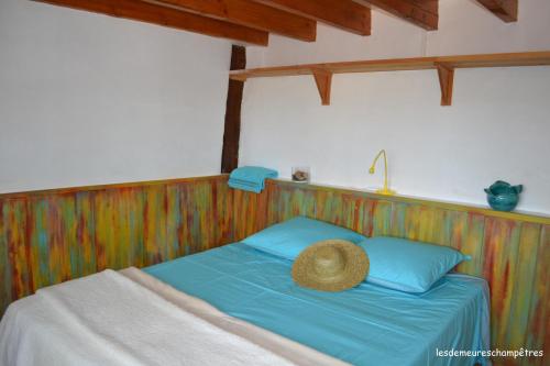 a bed with a straw hat on top of it at Les demeures champêtres in Jarnosse