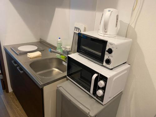 a microwave sitting on top of a counter next to a sink at Apartment Hotel KANSO in Kyoto
