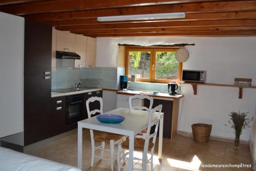 a kitchen with a table and chairs in a room at Les demeures champêtres in Jarnosse