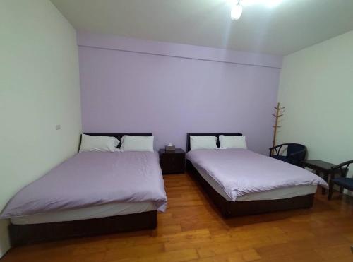 two beds in a room with white walls and wooden floors at Lanting Yazhu B&B in Renai